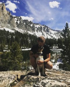 Anthony K. with his dog in front of a mountain