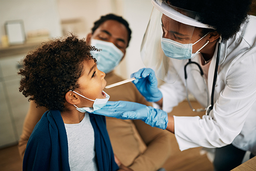 Family doctor examining throat of a small boy